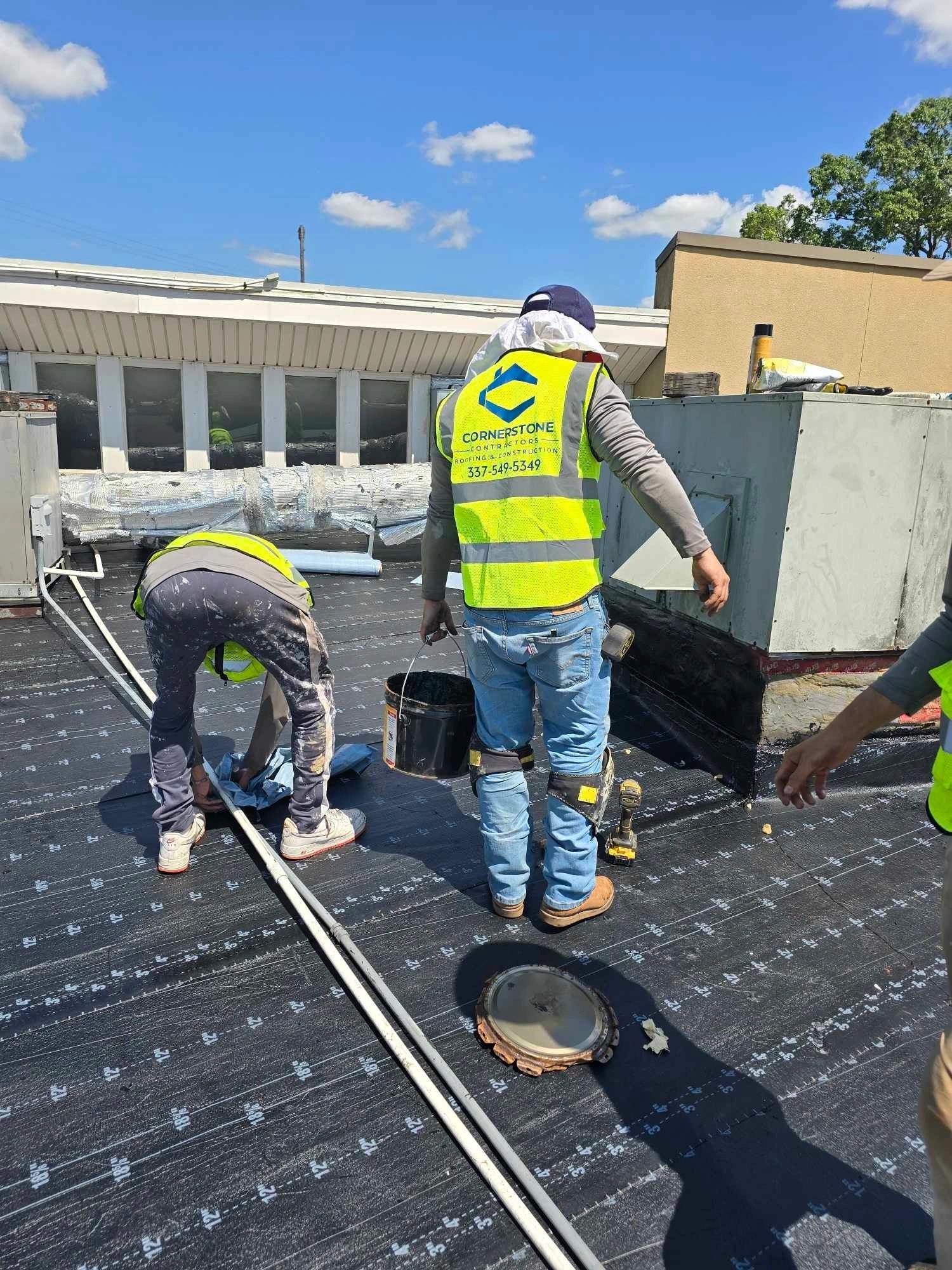 Cornerstone crew member in a hi-vis vest working on a low-slope commercial roof